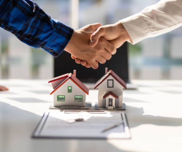 Real estate agents shake hands after the signing of the contract agreement is complete.